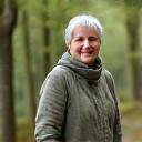 Nainen, Anna, hymyilee rauhallisesti ulkona, taustalla sumuinen metsä. Hän näyttää stressittömältä ja levänneeltä.