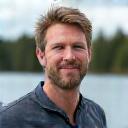 Pekka Järvinen, kokenut kiipeily- ja melontaopas hymyilemässä järven rannalla.